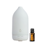 A white essential oil diffuser with a minimalist design stands next to a small amber glass bottle of doTERRA Citrus Bliss essential oil on a solid white background.