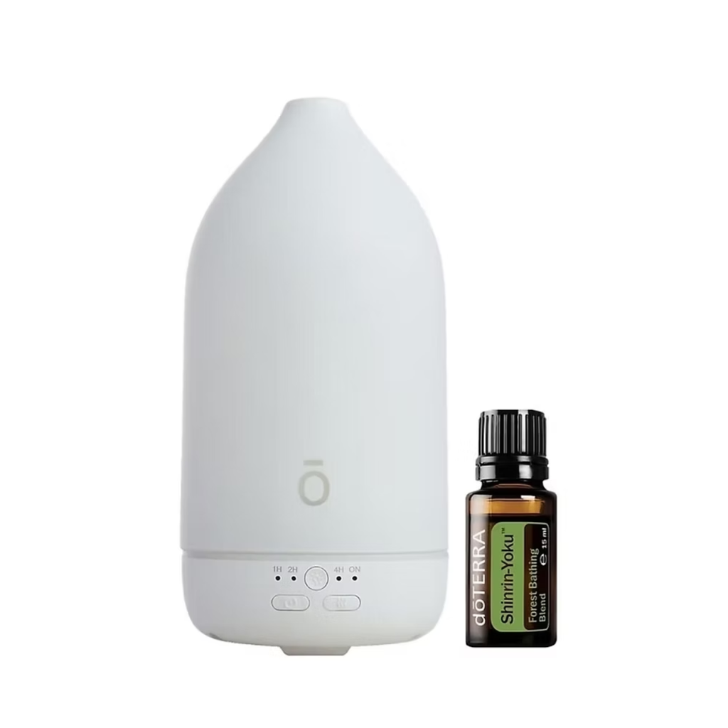 A white electronic diffuser bottle shown next to a small amber glass essential oil bottle labeled doTERRA Shimmer Road on a plain white background.