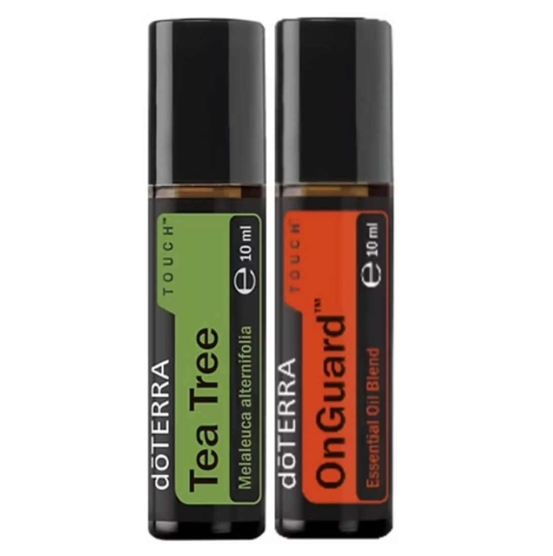 Two 10 ml doTERRA essential oil roller bottles standing side by side on a plain white background. The left bottle is labeled Tea Tree with a green label, and the right bottle is labeled OnGuard with an orange label.