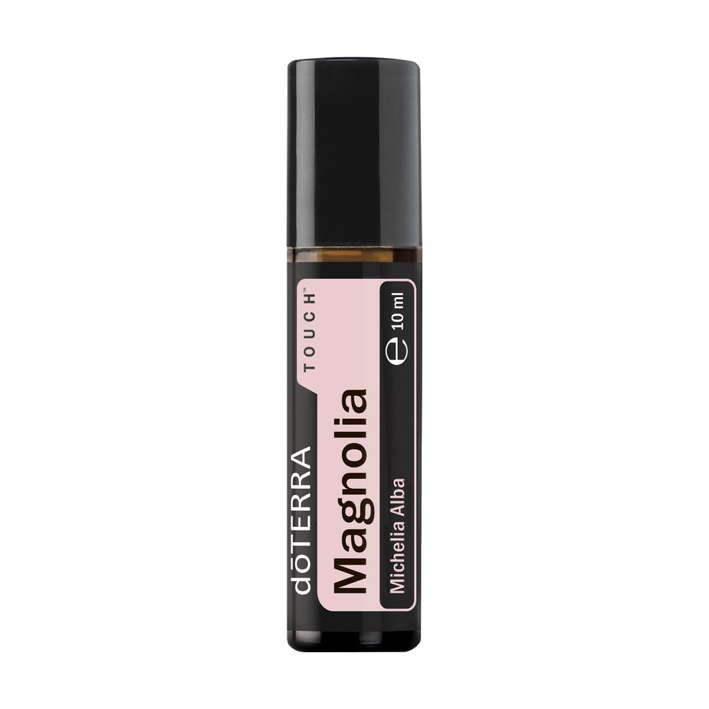 A 10 ml roll-on bottle of döTERRA Magnolia essential oil on a solid white background. The bottle is dark amber glass with a black cap and features a pink and black label with white text.