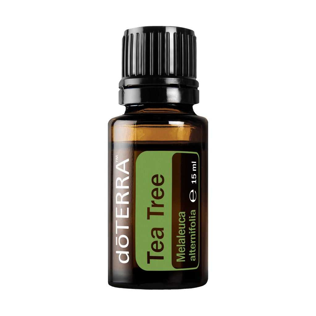 A 15 ml bottle of doTERRA Tea Tree essential oil on a solid white background. The bottle is made of amber glass, featuring a black ribbed cap and a label with a green and dark brown design.